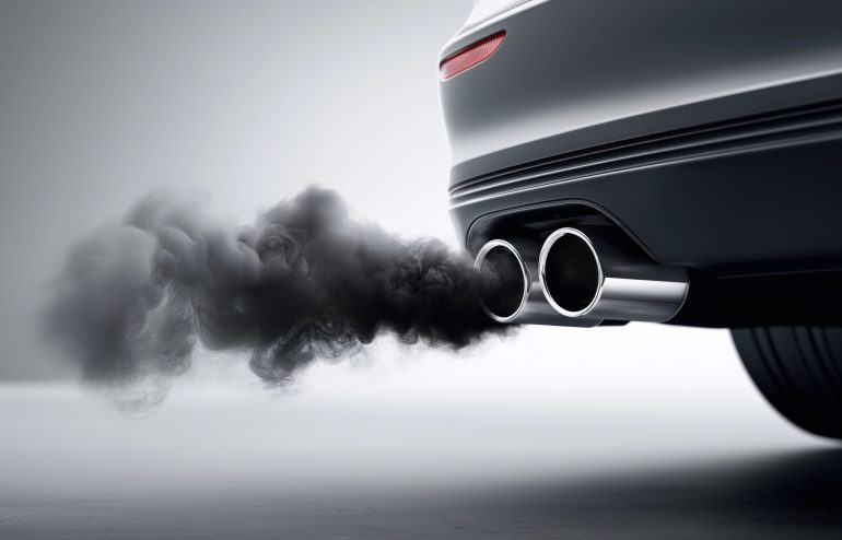 A car is emitting black smoke from its exhaust. The smoke is thick and billowing, creating a sense of pollution and environmental impact